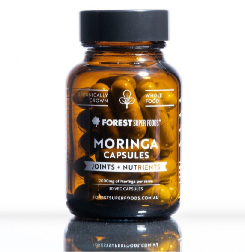 Amber glass jar of Forest Super Foods moringa capsules labeled for joints and nutrients with black lid on white surface